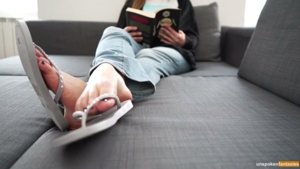 POV foot fetish scene with bare soles in focus while someone reads on the couch on girlsasian.net