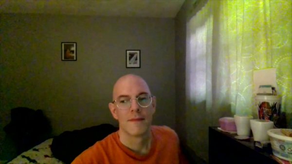Bald man with glasses sits thoughtfully in a softly lit room on girlsasian.net